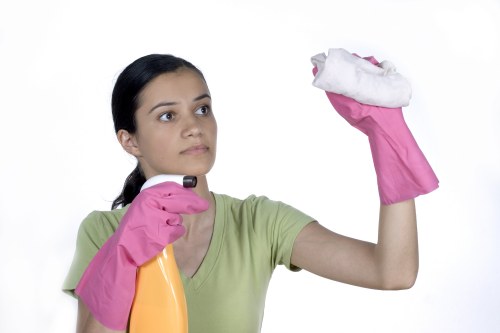 Office cleaner sanitising shared workplace surfaces